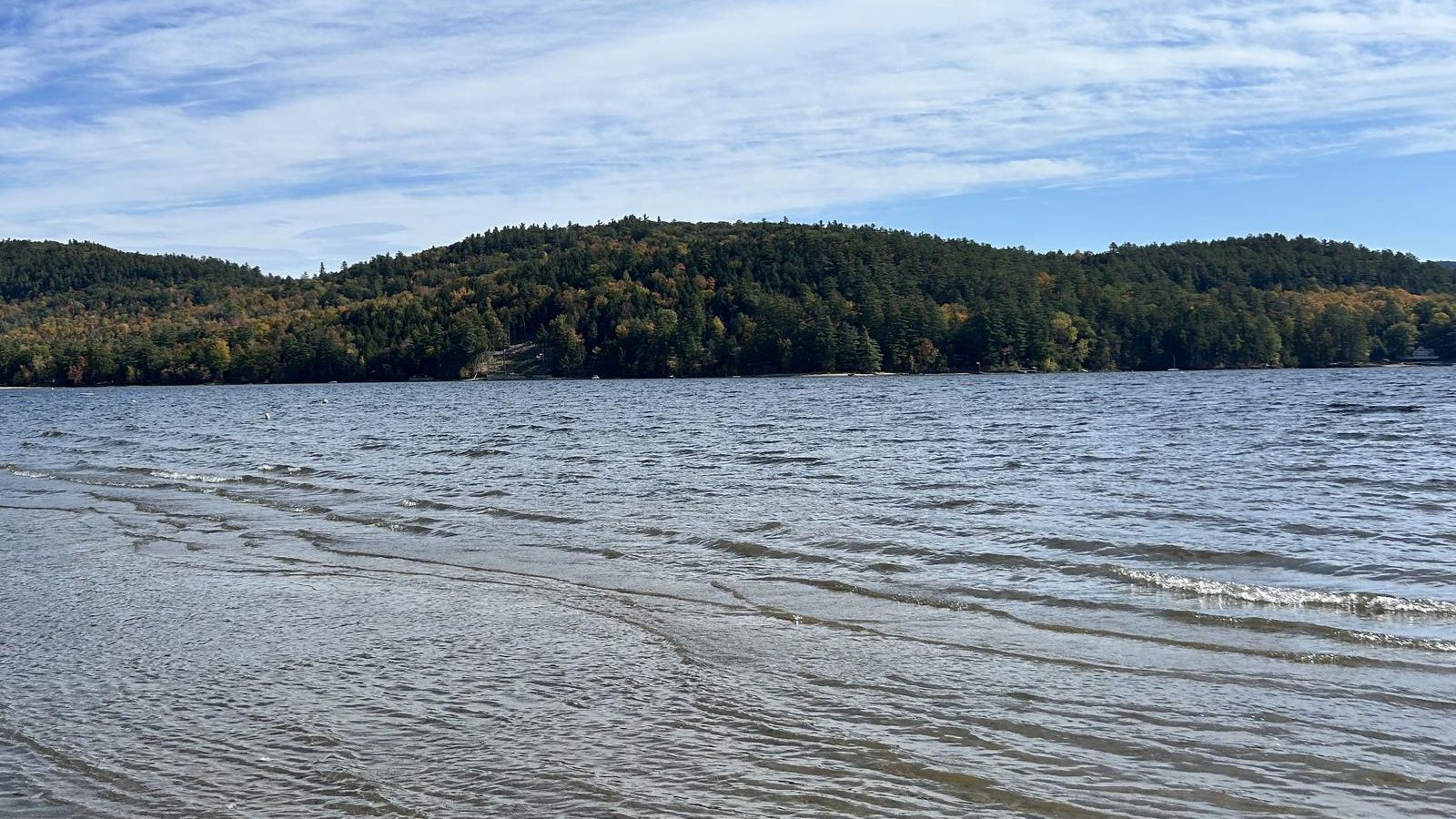 Adirondack lake with forested hills under a blue sky
